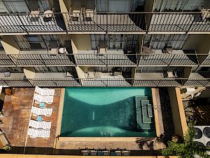 An aerial view of a hotel pool with lounge chairs and balconies.