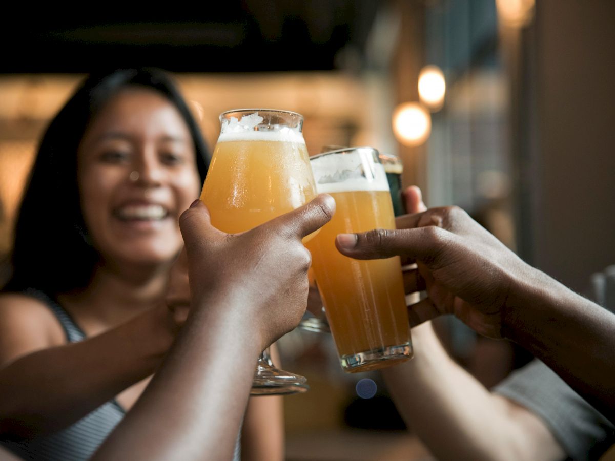 People are clinking glasses filled with beer, smiling and enjoying a cheerful moment together.