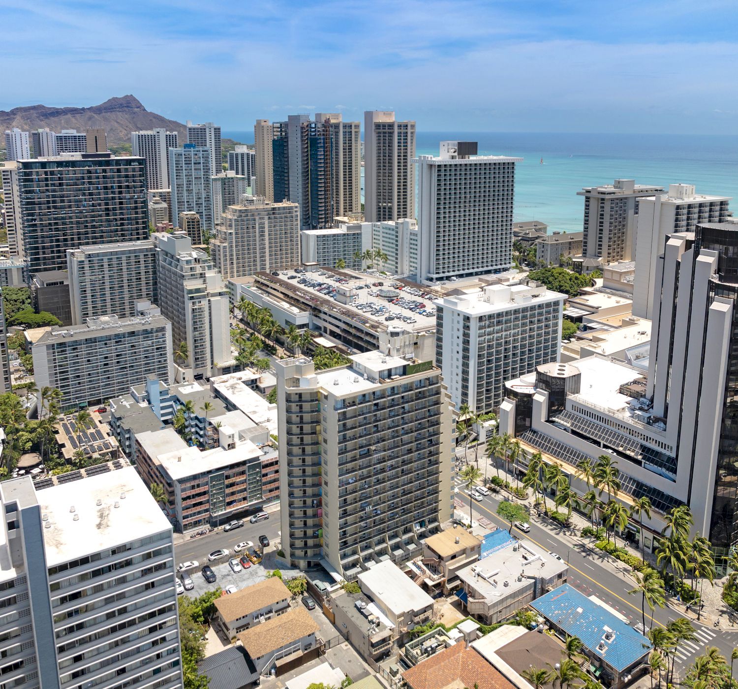 An aerial view of a city with modern high-rise buildings, a coastline, and a mountain in the background.