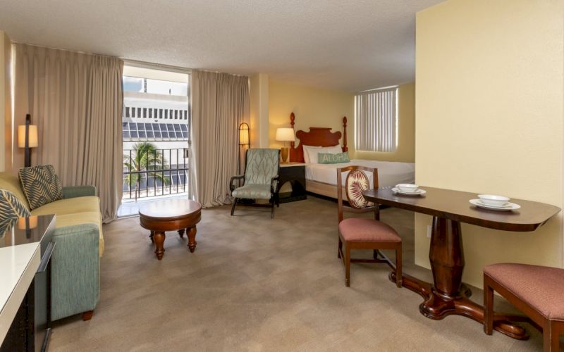 A wide-angle view of a hotel suite with a living area, dining table, and bedroom.