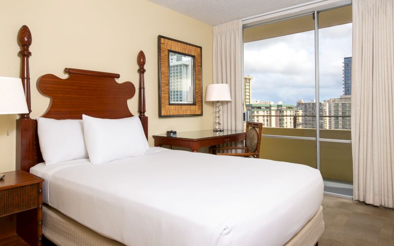A hotel room with a large bed, desk, and city view.
